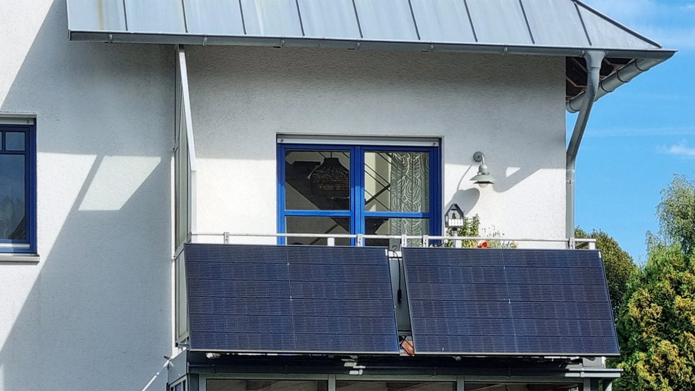 Balcony solar installation with panels facing outward on an apartment railing